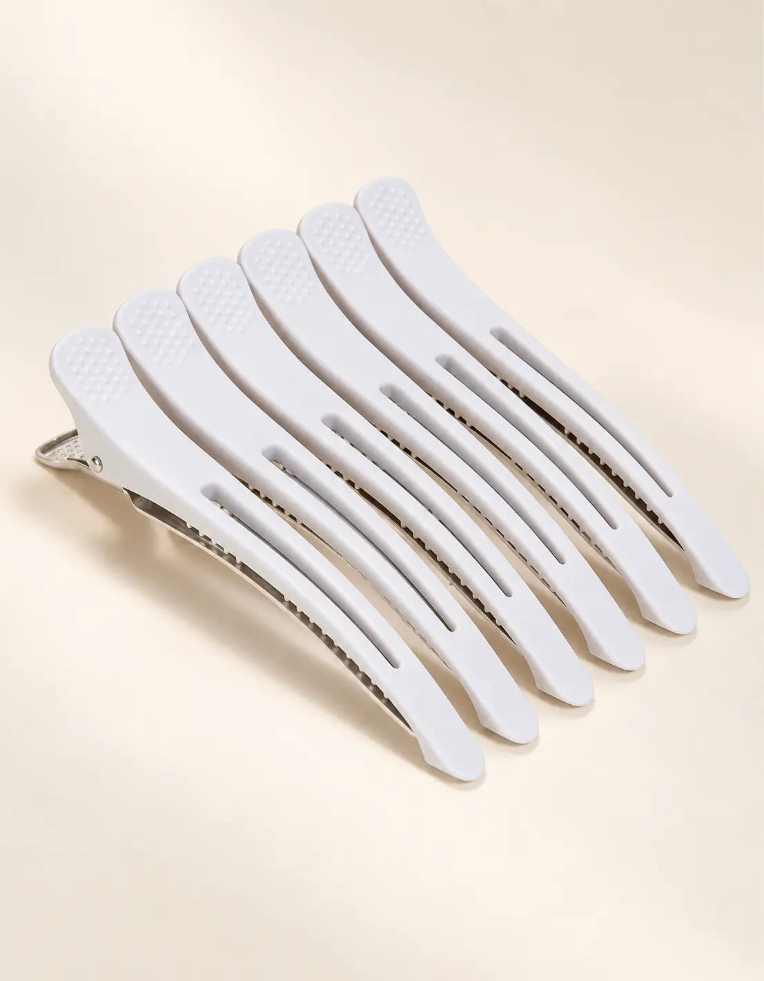 Set of white BELARO professional hair sectioning clips on a cream background