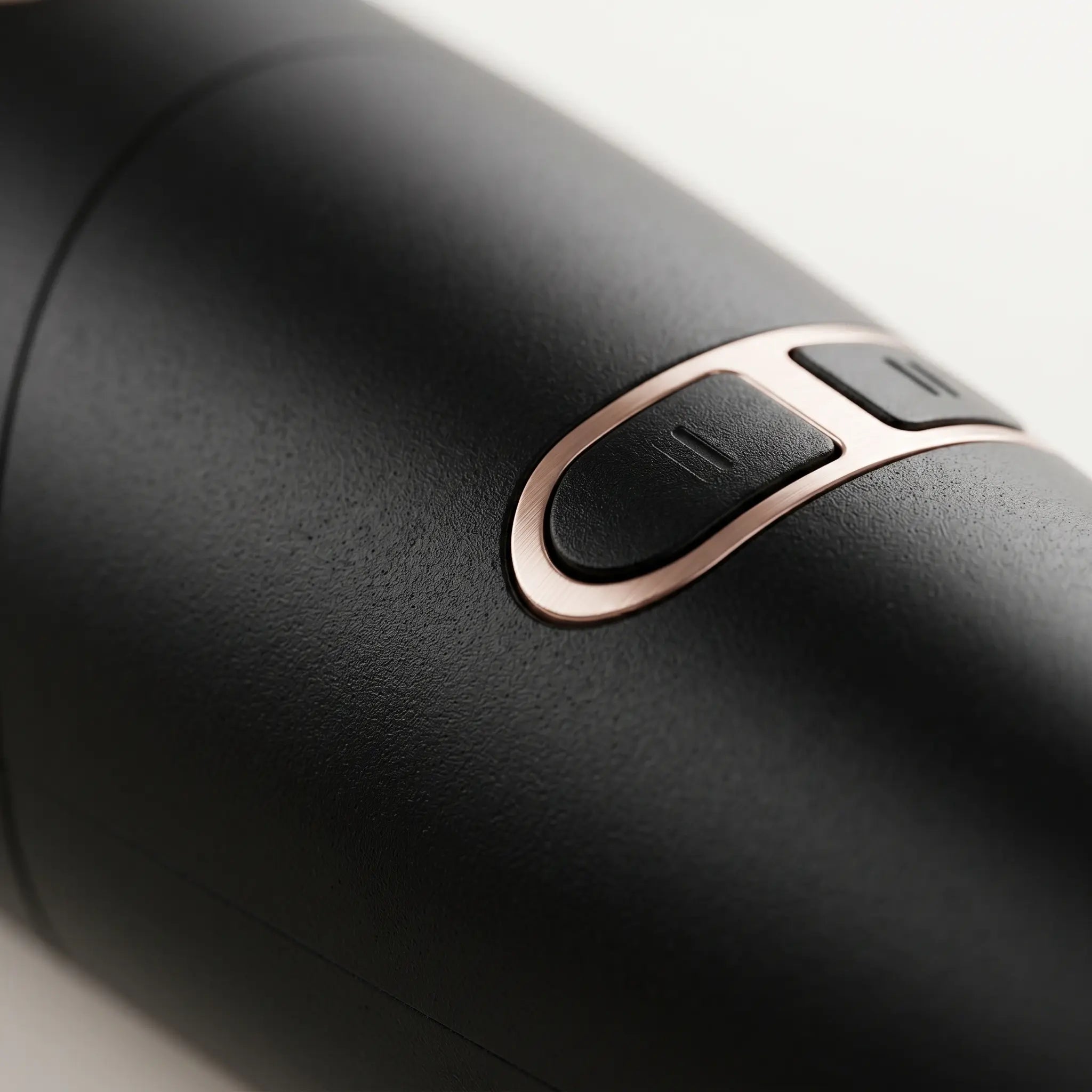 Close-up of a BELARO hair styling tool showing rose gold control buttons and matte black finish