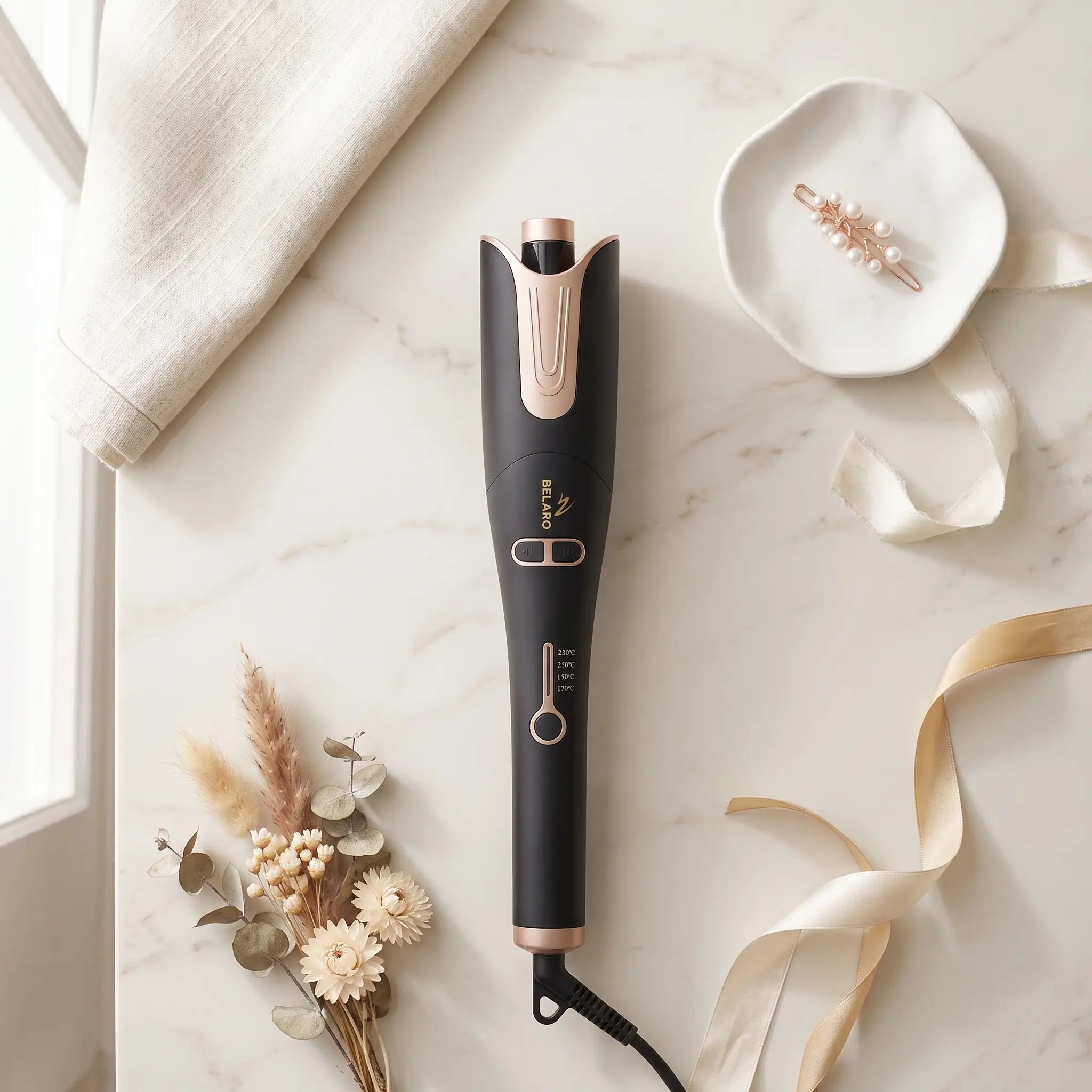BELARO Intelligent Curl hair styling tool arranged on a marble surface with soft beauty accessories