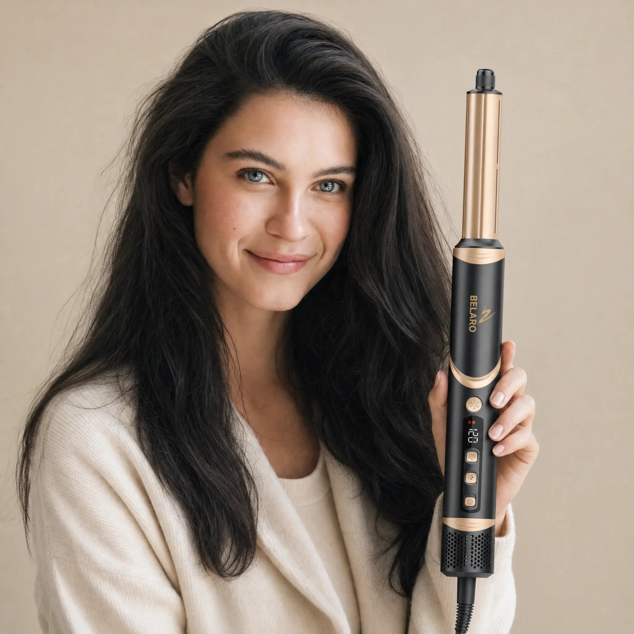 Woman holding the BELARO 8-in-1 hair styler with soft voluminous hair on a cream background