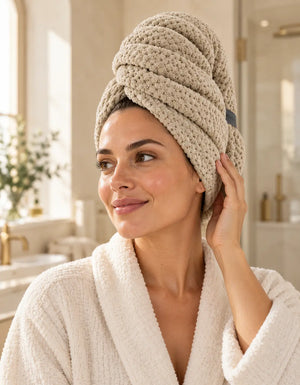 Woman wearing a beige BELARO quick-dry hair towel wrap in a bright bathroom