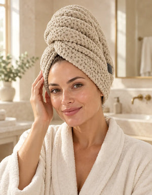 Woman wearing a beige BELARO quick-dry hair towel wrap in a bright bathroom