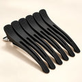Set of black BELARO professional hair sectioning clips on a cream background